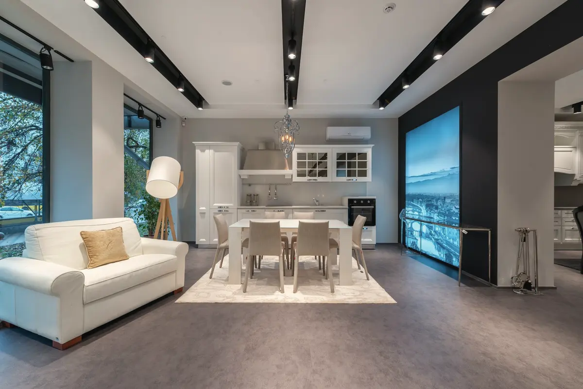 Showroom amplo e iluminado com sofá branco, mesa de jantar e cadeiras em exposição